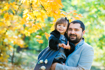 Little girl with dad playing in autumn park