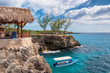 Caribbean rocky beach with turquoise water, tourists boat and lighthouse in Negril, Jamaica. 
