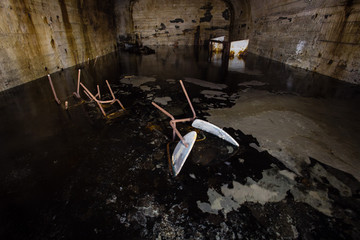 Underground mine shaft iron ore tunnel gallery with flooded water and chairs