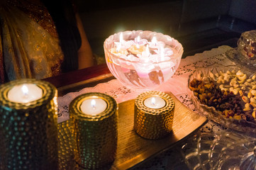 Girl in traditional indian saree sitting with beautiful candles on diwali. A glass bowl of floating candles, golden candles of different heights and dry fruits are clearly visible