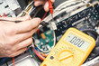 Technician hands with voltmeter above computer motherboard. Repair of computers concept. Toned with selective focus