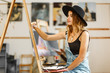 © proimagecontent - Female artist wears black hat draw picture indoor the studio