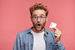 © wayhome.studio  - Portrait of astonished bearded man holds condomn, waits for lover in bedroom, wants to use it in short time. Handsome young guy advertises contraceptive, stands against pink studio background