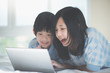 © lalalululala - Asian children lying in bed and using laptop
