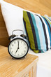 © wirojsid - Vintage retro alarm clock on bed side table at 7 o'clock