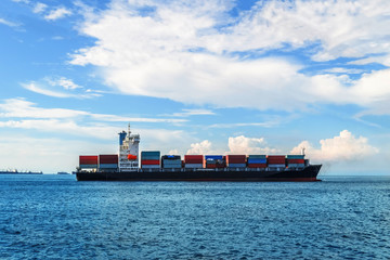 Large gray general cargo vessel moving in still water. Cargo shipping, delivery and logistics concept.