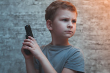 Boy With A Gun In His Hand Against The Brick Walls,