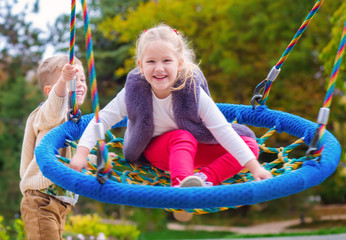 two happy little children having fun on a swing