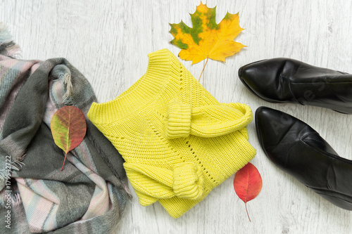 Plakat Jasny sweter, szalik, czarne buty i jesienne liście. Modna koncepcja