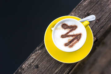 Wall Mural - Yellow coffee cup on a wooden board