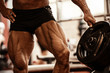 Close-up of bodybuilders muscular legs. Athlete man doing workout exercise in gym.