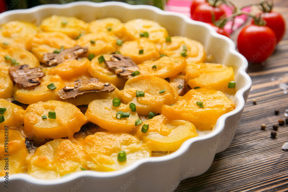 Delicious potato casserole in baking dish on wooden table