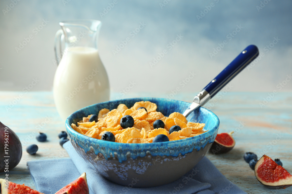 Dish with cornflakes and milk on table