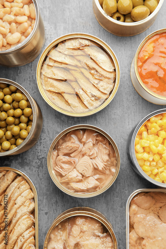 Foto  Open tin cans with different food on table
