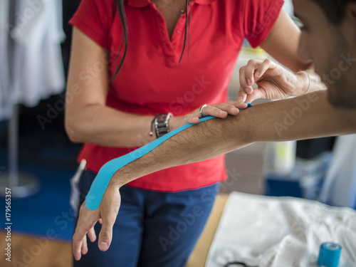 Fotografía fisioterapista applica tape dopo massaggio per il dolore a un giovane sportivo