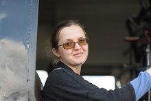 Model Girl In Glasses Inside The Cab Of The Control Steam Engine Locomotive. Driver