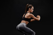© nazarovsergey - Side view portrait of a young woman doing squats on black background.