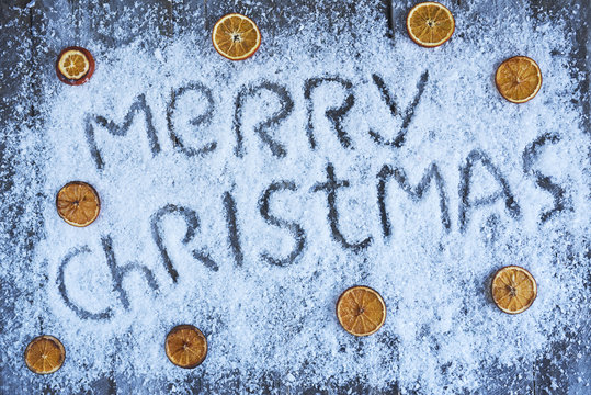 Merry christmas hand drawn lettering with orange fruit over wooden blue board
