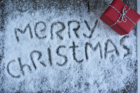 Merry christmas hand drawn lettering with gift box over wooden blue board
