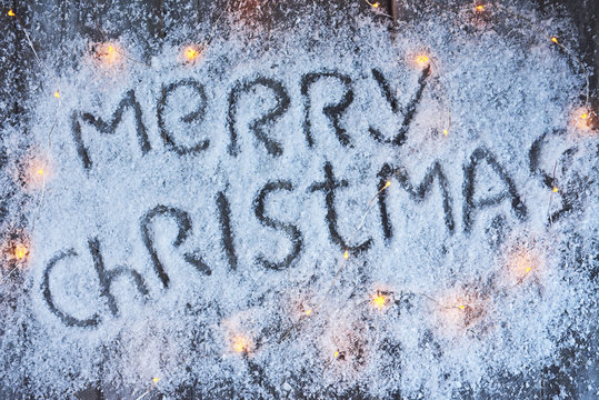 Merry christmas hand drawn lettering with lights over wood board