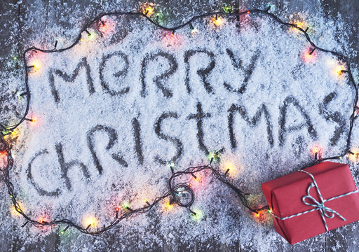 Merry christmas hand drawn lettering with lights over wood board