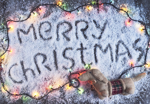 Merry christmas hand drawn lettering with lights over wood board