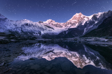 Wall Mural - Amazing night scene with himalayan mountains and mountain lake at starry night in Nepal. Landscape with high rocks with snowy peak and sky with stars reflected in water. Beautiful Manaslu, Himalayas
