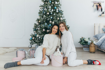 Wall Mural - Two happy, stylish and beautiful girls opened Christmas gifts and received a the rabbit.