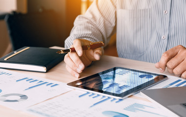 Businessman looking graph and summary report on digital tablet screen with analysis data result.