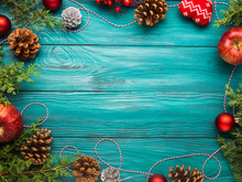 Christmas Dark Green Frame Background With Pine Cones, Red Baubles And Twine, Apples. Wooden Table Texture