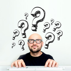 Portrait of an attractive stressed geek man with question mark icons surrounding his head - Problem concept