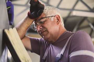 Senior man in workshop. Worried  man reading his planner.