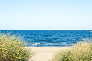 Beach view from the sand dunes with path and footsteps