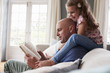 © Guerilla - Father reading a book while daughter sitting on his shoulder at home