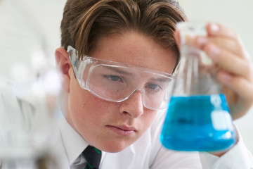 Wall Mural - male pupil conducting chemistry experiment in science class