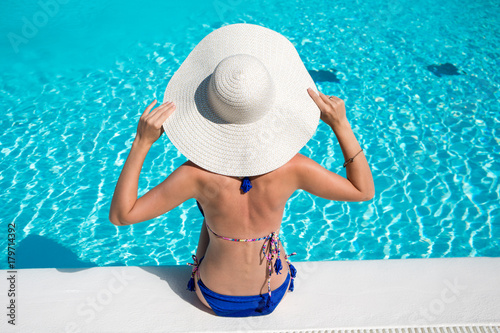 Plakat Młoda kobieta siedzi przy krawędzi basenu