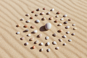 pattern of colored pebbles in the shape of a circle on clean sand