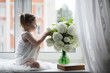 © alexkich - A little girl is sitting on the windowsill. A bouquet of flowers