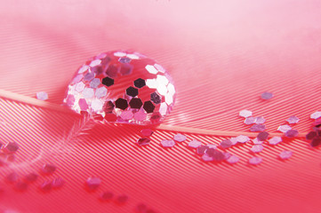 Drops with sparkles on a pink feather. Gentle soft beautiful artistic close-up photo. Bright abstract macro picture.