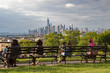 New York's diversity represented by people sat on a bench in Sunset Park, Brooklyn, admiring the view of Lower Manhattan on a sunny summer's day