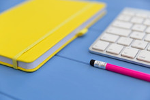 Yellow Notebook Wireless Computer Keyboard And Pink Pencil