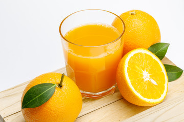 Poster - Glass of fresh orange juice with group of orange on a wooden box isolate on white background, Selective focus on glass.