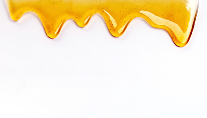 dripping honey seamlessly repeatable from the top over white with copyspace.
