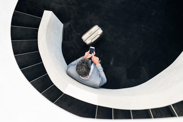 Wall Mural - Businessman with smartphone standing at staircase.