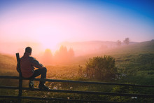 Man Sitting On A Wooden Fence Enjoy The Misty Morning
