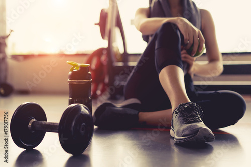 Fotomural Woman exercise workout in gym fitness breaking relax holding apple fruit after training sport with dumbbell and protein shake bottle healthy lifestyle bodybuilding, Athlete builder muscles lifestyle