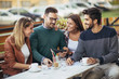 © Mediteraneo - Group of four friends having fun a coffee together. Two women and two men at cafe talking laughing and enjoying their time