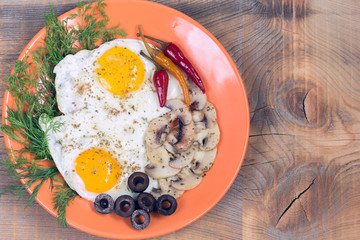 Fried two eggs with champignons, olives, dill and red chili pepper