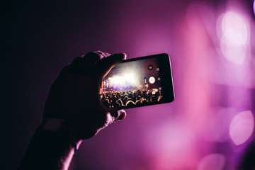 Close-up picture of person holding camera on music festival