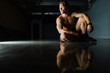 © photominus21 - Fashion portrait of a fitness model of a bodybuilder man sitting on the mirror floor after a workout.